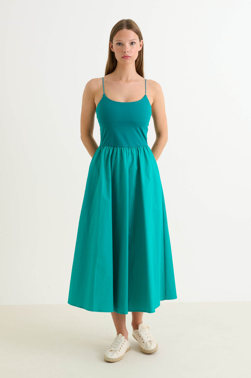 Woman wearing a teal dress on a white background